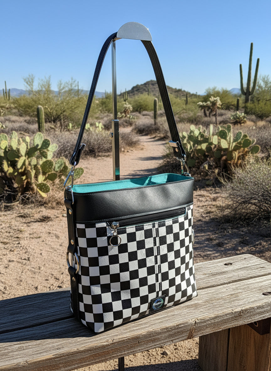 Checkered bag with black strap on a gray background